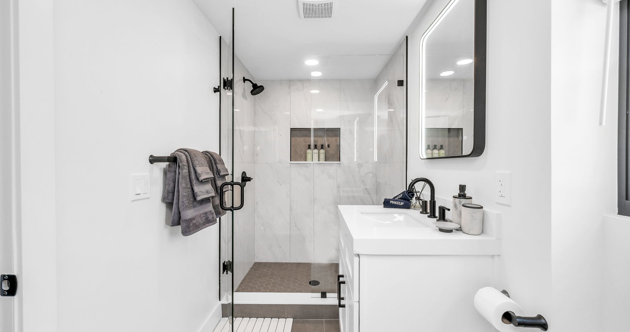 Step into a brand-new, spa-inspired primary bathroom featuring a sleek glass-enclosed walk-in shower with rainfall showerhead, designer vanity with LED mirror, and elegant finishes throughout.