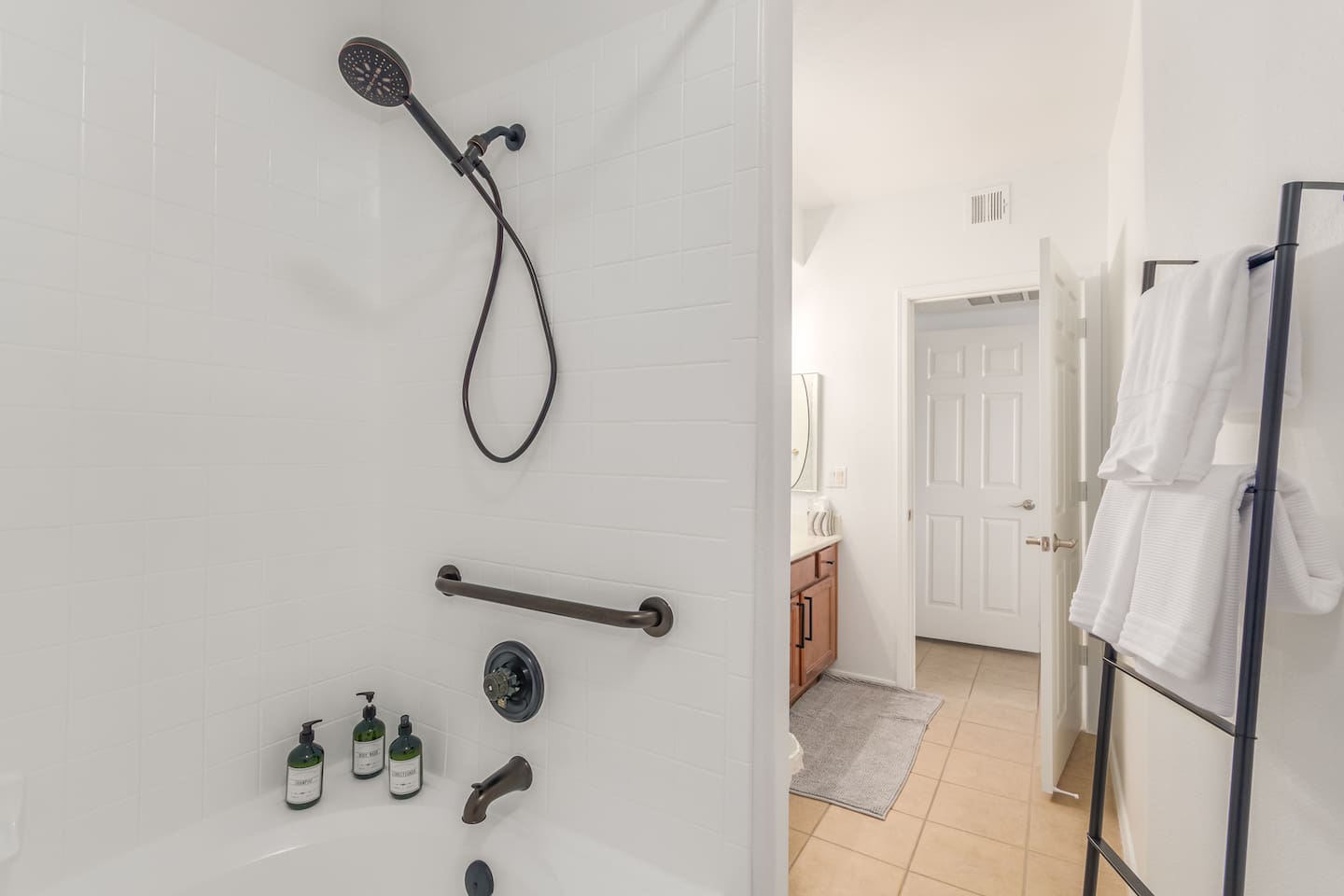 Bathroom with tub/shower combination, handheld showerhead, grab bar, towel rack, and clean essentials for daily routines.