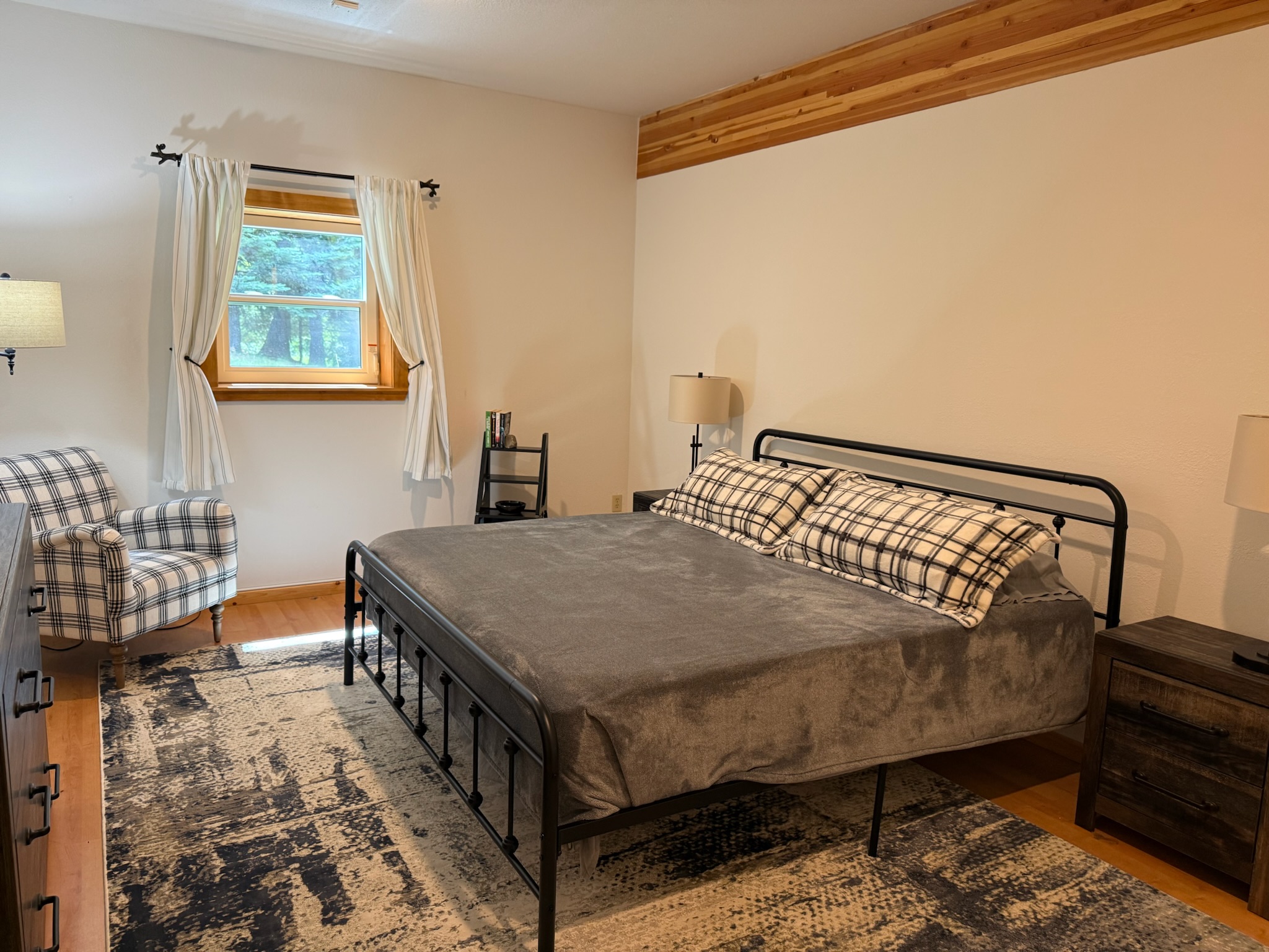 Downstairs guest room with King bed and sitting chair, view to lake and yard