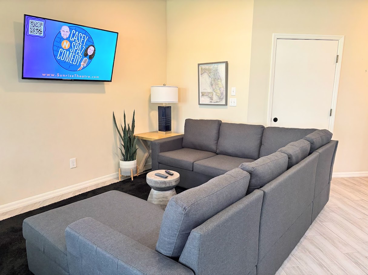 Comfortable living room featuring a large sectional sofa, wall-mounted TV, and clean modern flooring.
