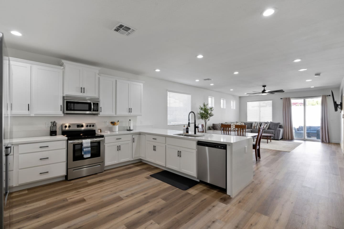 Full kitchen with stainless steel appliances, white cabinetry, dishwasher, plenty of counter space for everyday meals and overview to living area