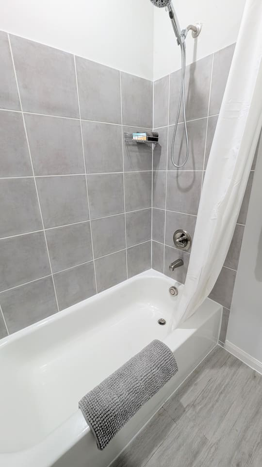 Full tub/shower combo with fluffy towels and bath mat. 