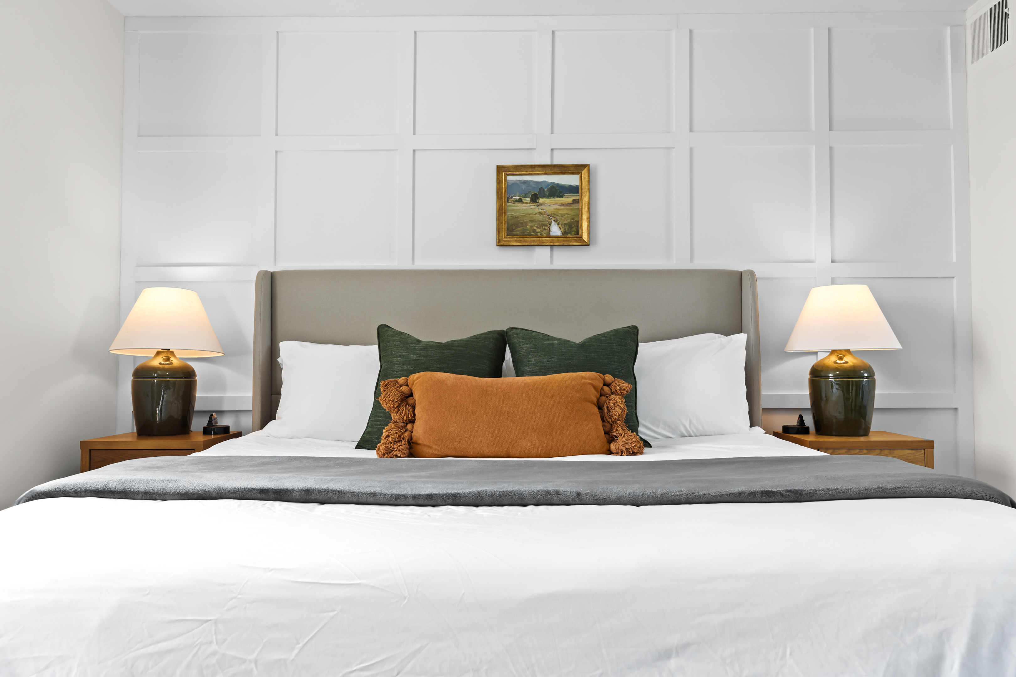 Cozy bed with accent pillows and stylish wall paneling.