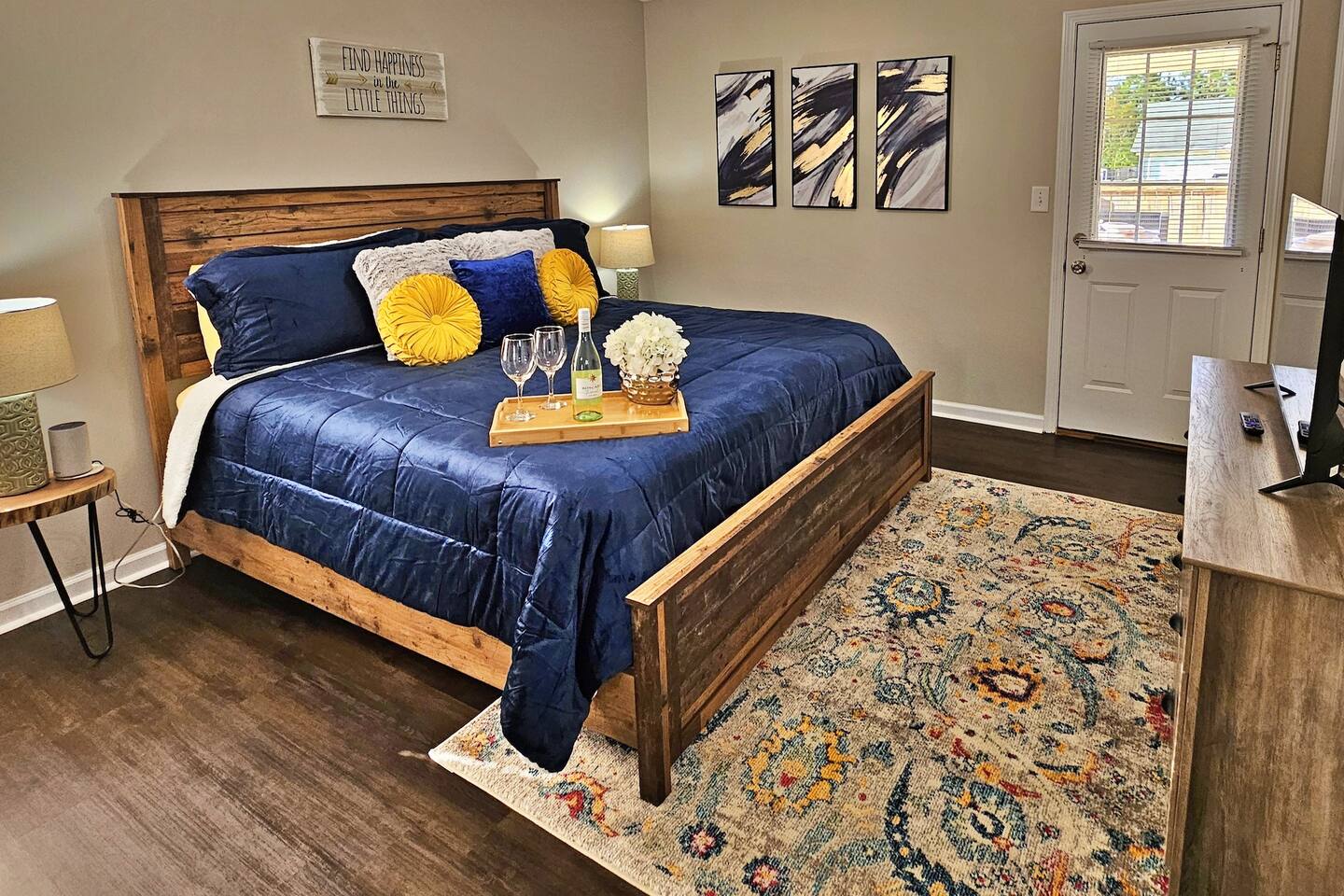 Relax in this farmhouse-style bedroom. There is a king bed along with a flat-screen smart TV. Step out the door to the back patio and fenced-in backyard. 