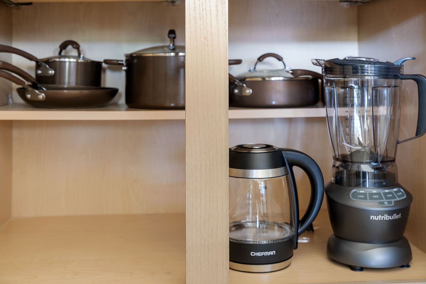 Discover a well-equipped kitchen cabinet featuring high-quality cookware and modern appliances, including a blender and electric kettle.