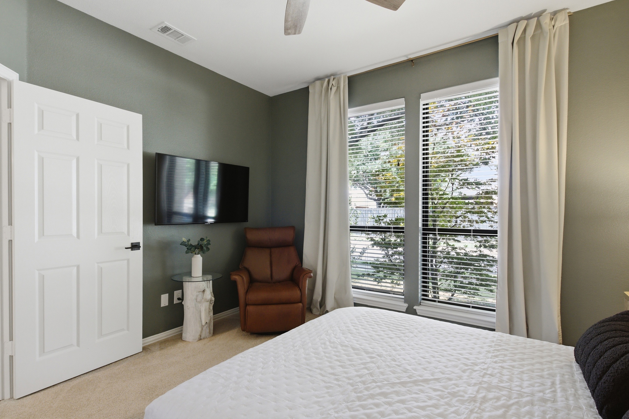 Guest Bedroom 2 featuring a Queen Bed, TV, leather recliner, lamps, and a calming green palette. A peaceful retreat that sleeps two comfortably.
