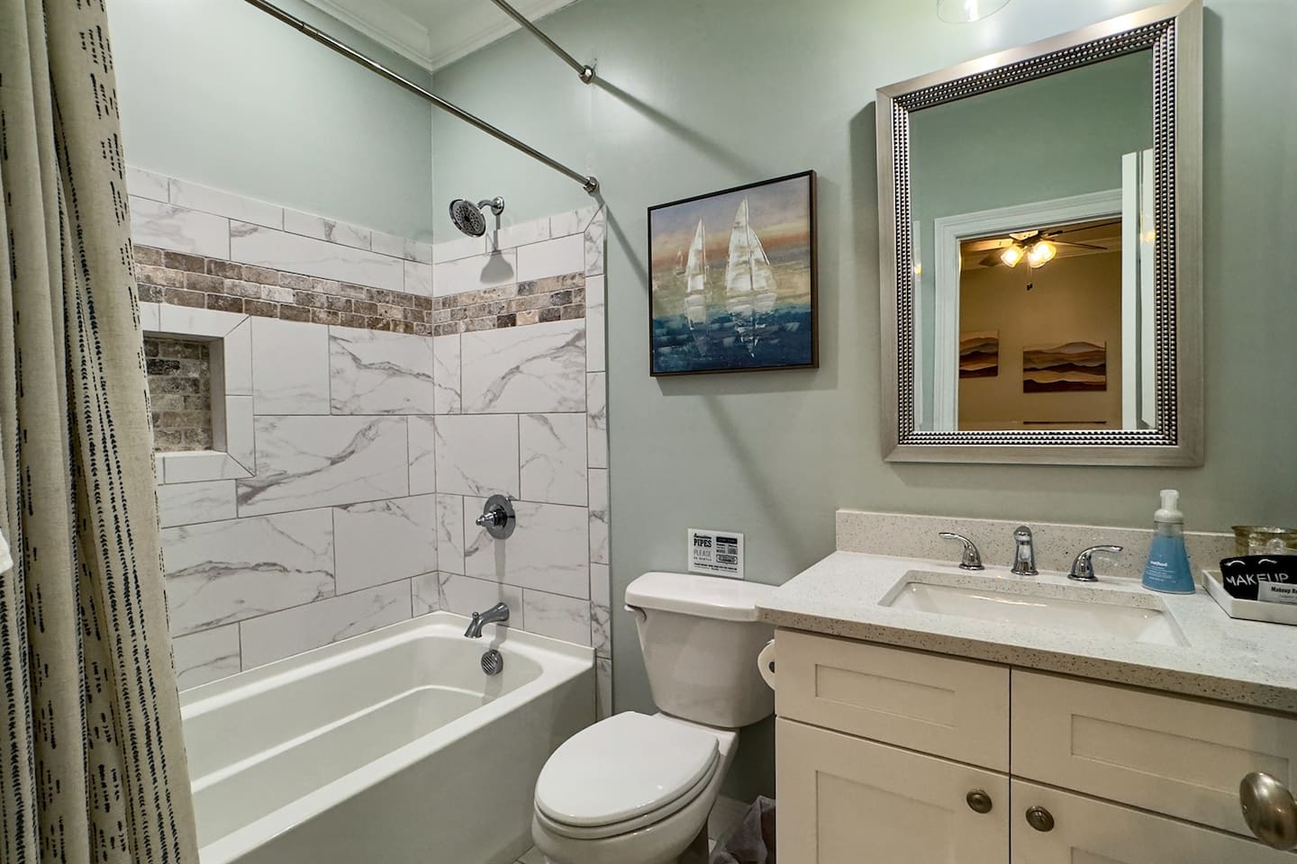 Updated bathroom with a tiled tub/shower combo, modern vanity, and coastal-inspired accents.