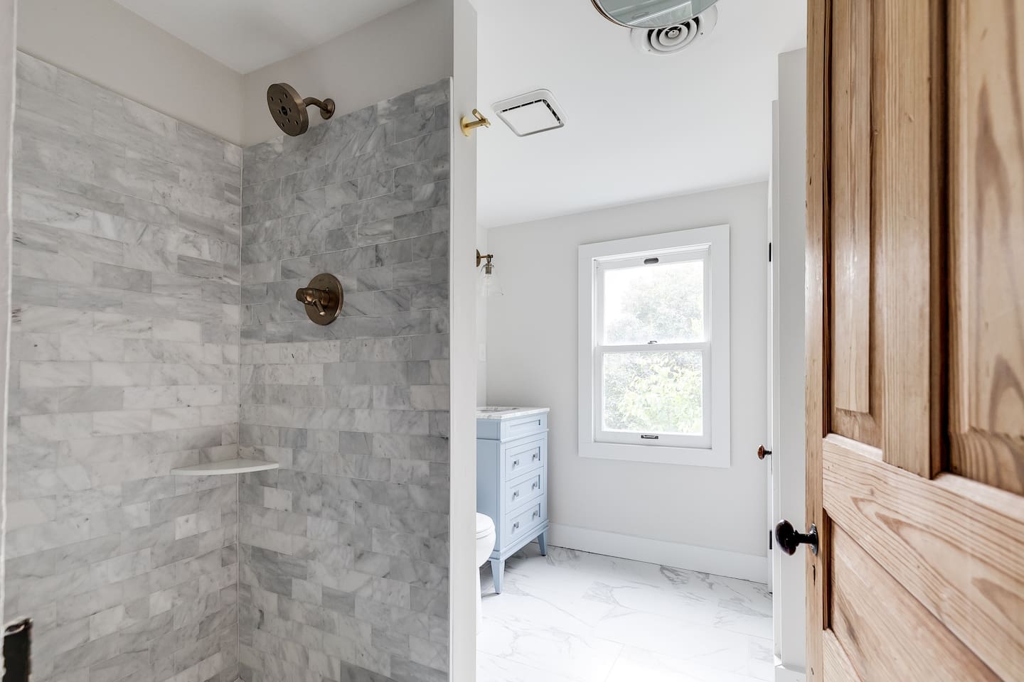 Ensuite Bathroom: Refresh in a sleek shower with marble accents and natural light streaming in!