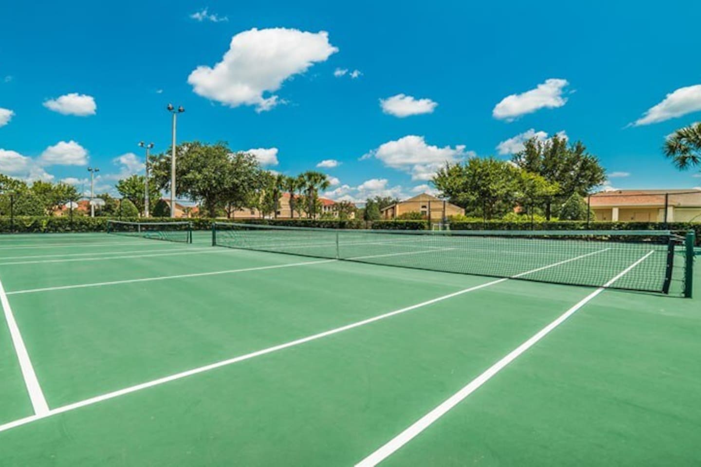 Outdoor tennis court under a bright blue sky.

