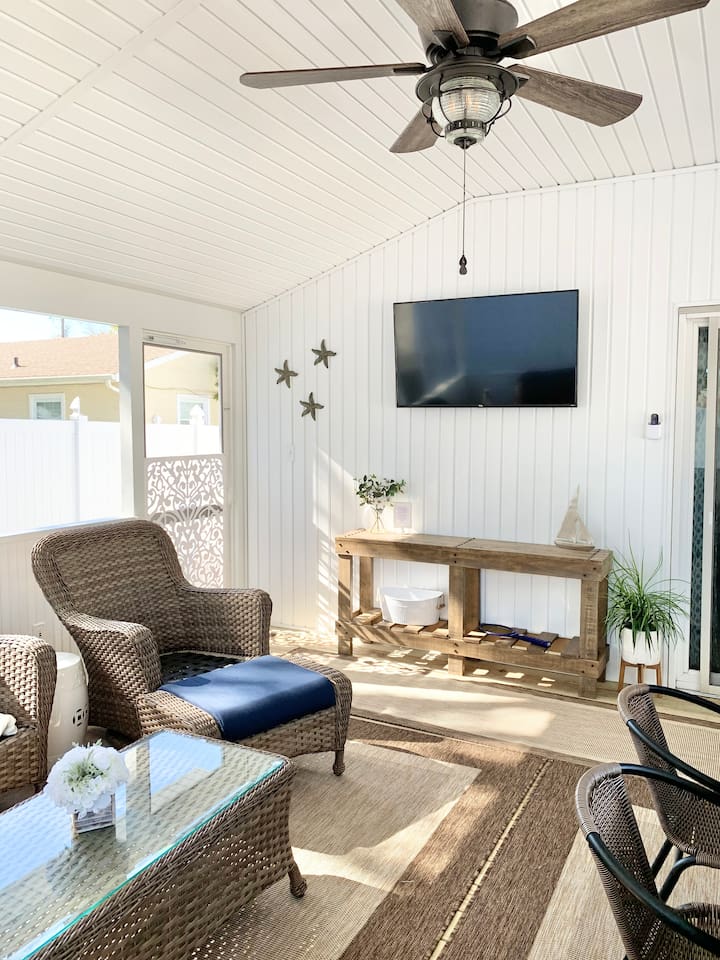 Experience the best of indoor-outdoor living in our screened-in sunroom. Kick back on navy wicker seating to watch the game or enjoy a meal at the large dining table—all while staying protected from the elements in a bright, coastal setting.