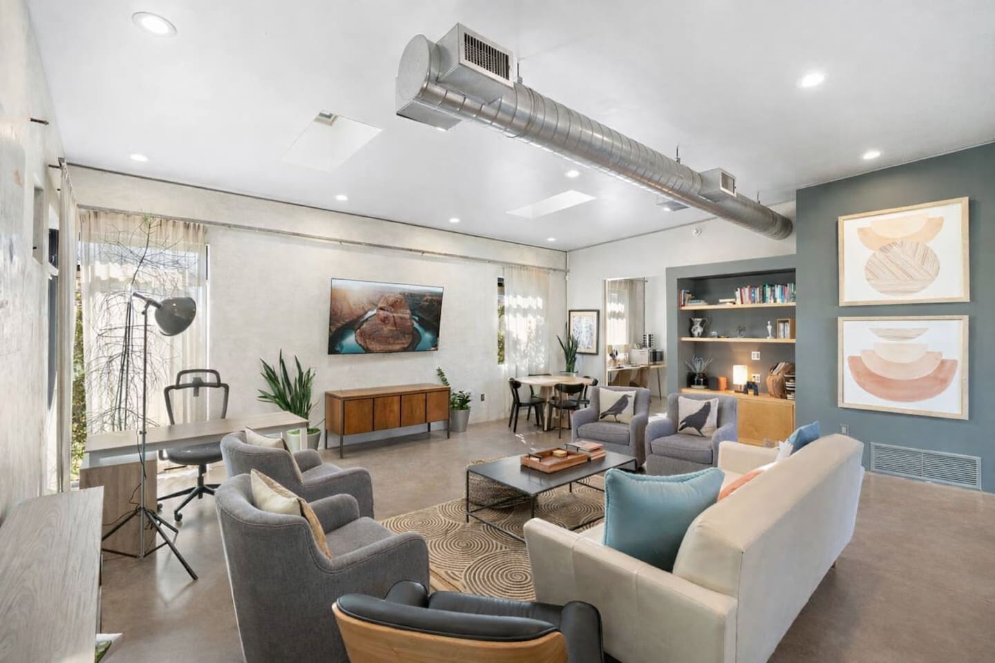 Open-concept living space with cozy seating, a workspace area, dining nook, and modern industrial touches throughout.