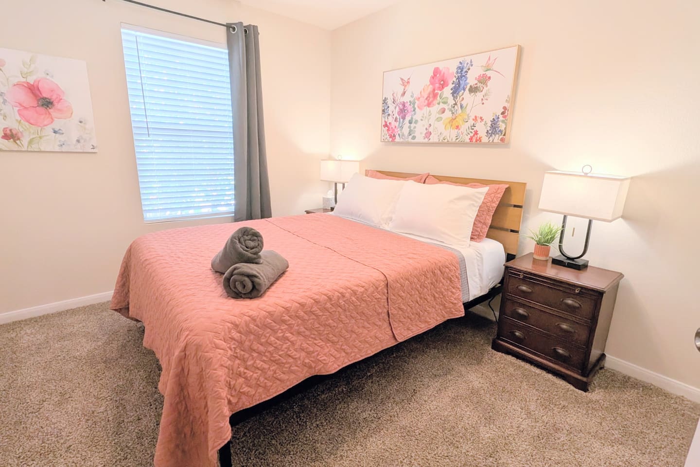 This bedroom features a comfortable queen bed with sheets, blanket, quilt and plush pillows. Convenient charging ports, room darkening curtains and blinds, alarm clock, and ceiling fan are provided. 