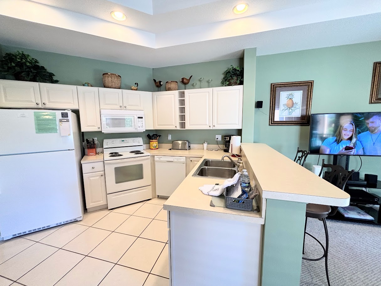 Fully equipped kitchen with full-size appliances, breakfast bar seating, and an open view into the living area.