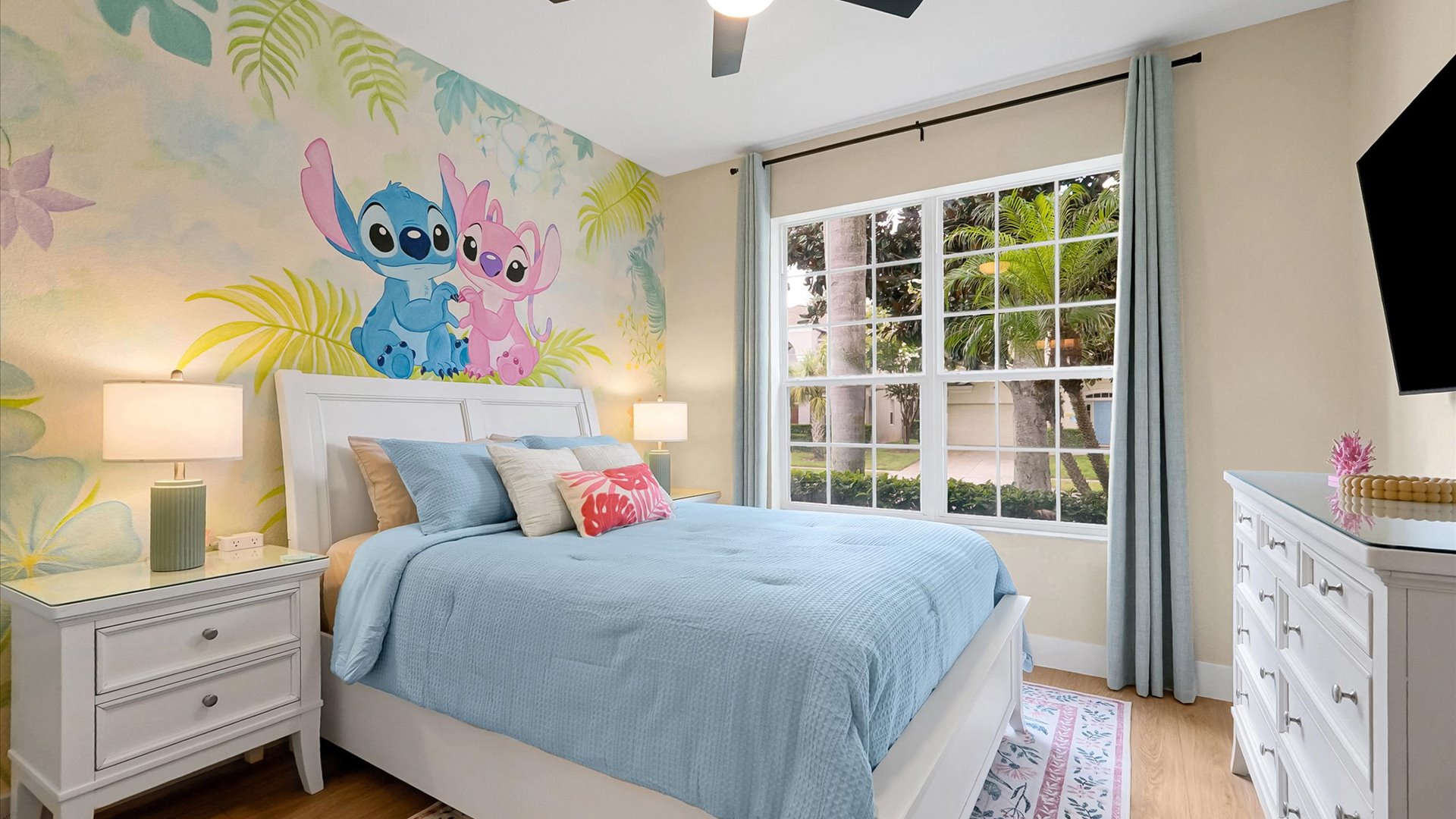 Stitch Queen Retreat: Queen-size bed framed by a colourful tropical mural, with closet storage and direct access to a private ensuite.