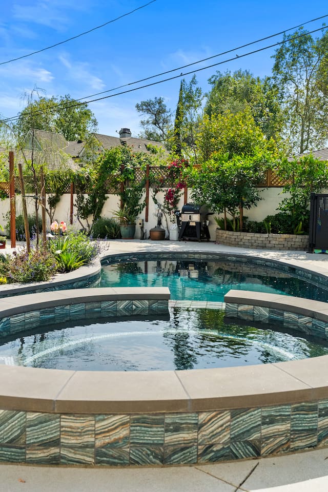 The tranquil beauty of the backyard, blending the soft glow of the houses with the shimmering pool.
