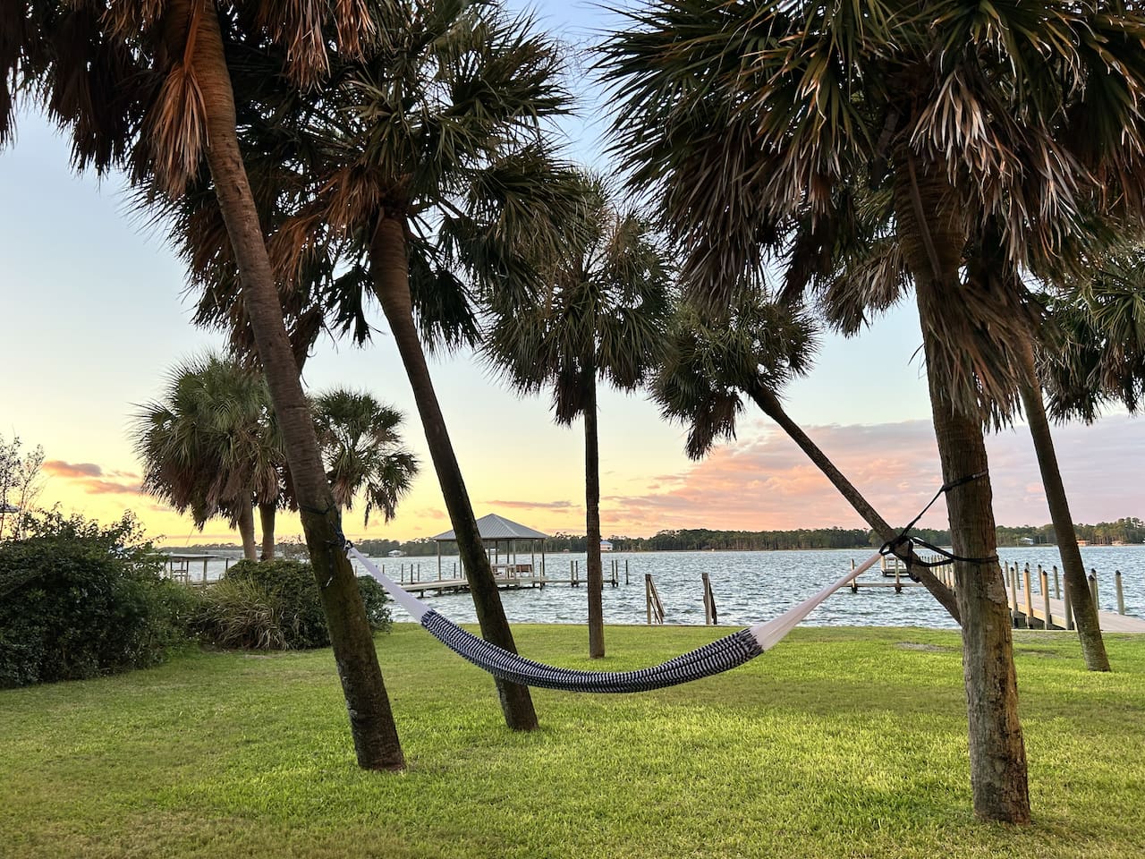 Relax in a bayfront hammock surrounded by palm trees, enjoying a tranquil waterfront view.