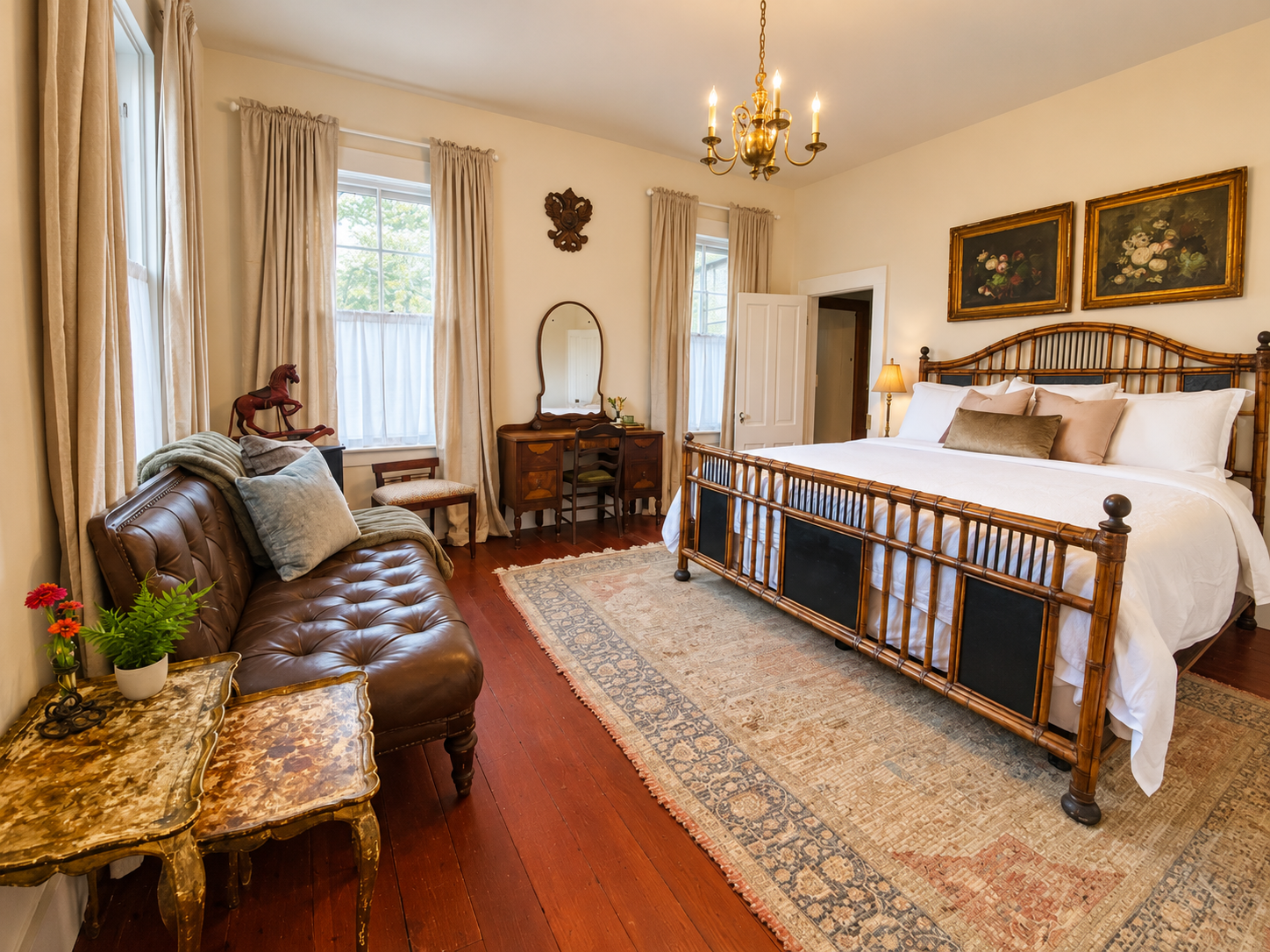 Boudoir de Bouge, our first-floor primary suite: plush bedding, room-darkening curtains, a Ralph Lauren leather sofa, and an antique vanity. An adjoining dressing room leads to your private en suite bath. 