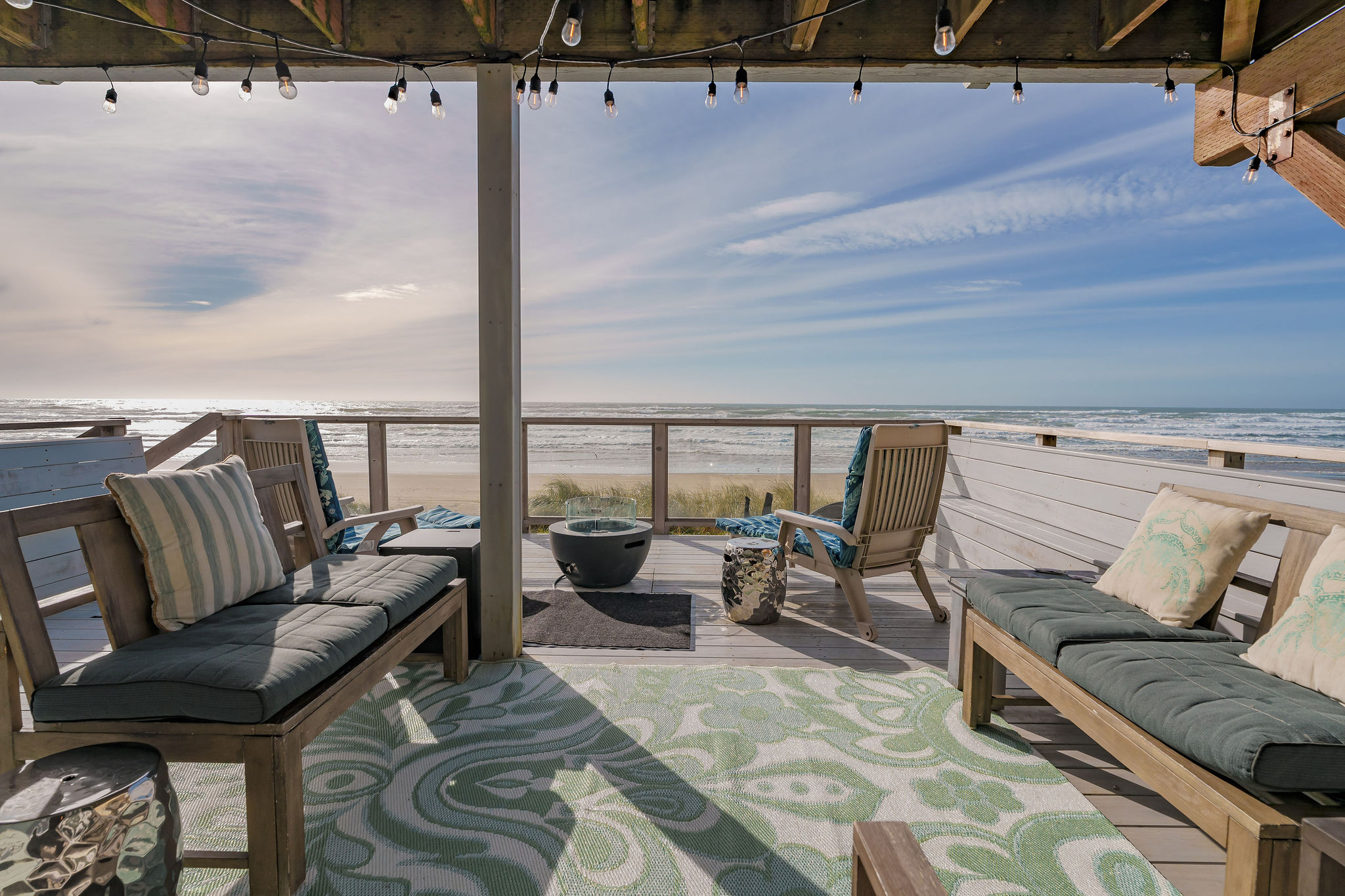 The deck is adorned with an array of comfortable outdoor furniture, including a propane bbq grill and string lights that invite relaxation