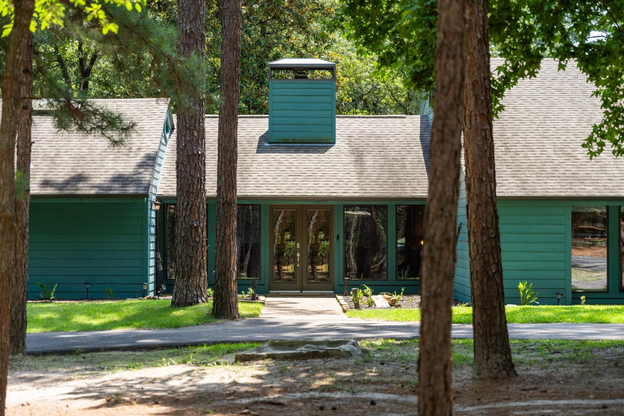Welcome to Teal Paradise! The lush front yard features greenery, double doors, and step-free access, blending beauty and accessibility—setting a serene tone for the comfort inside.