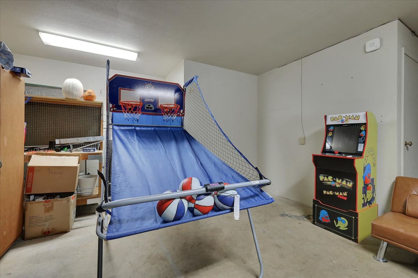Game room with arcade games, basketball toss, sofa seating, and extra space to hang out.
