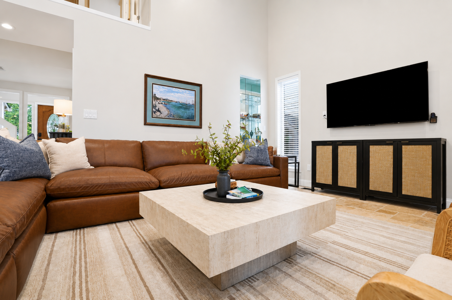 Cozy living room with a large sectional, modern TV console, and clean minimalist design. Bright, comfortable space perfect for relaxing and unwinding.