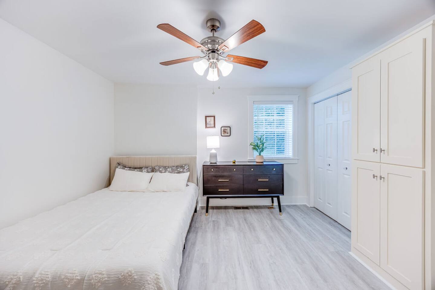 Cozy bedroom featuring a minimalist ceiling fan and a window that lets in fresh air and natural light for a peaceful retreat.
