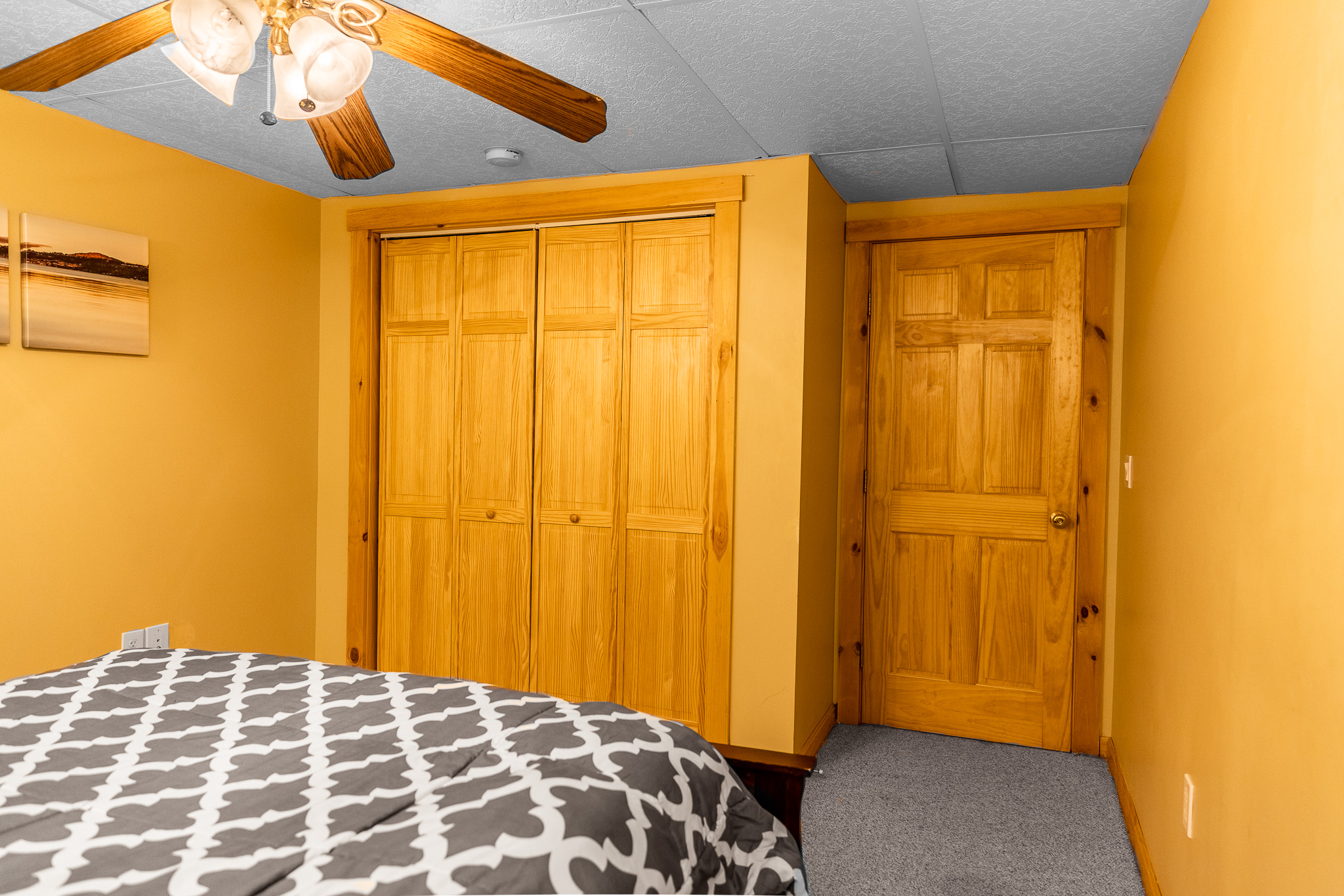 Downstairs bedroom with queen bed, closet, ceiling fan.