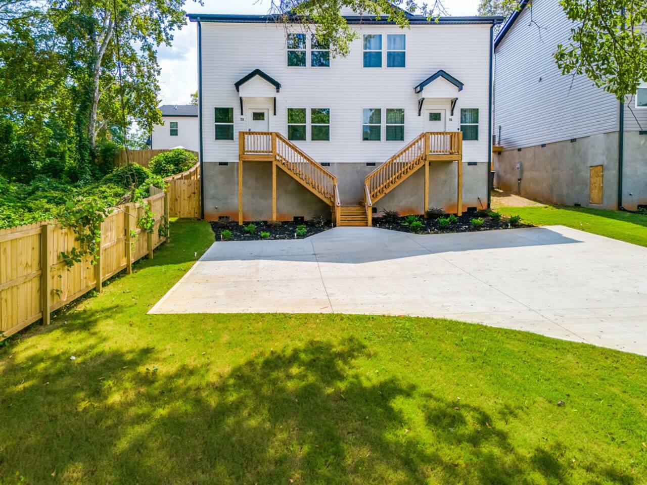 Well-maintained front yard with lush green grass, a driveway, and a cement parking pad for convenient parking access.