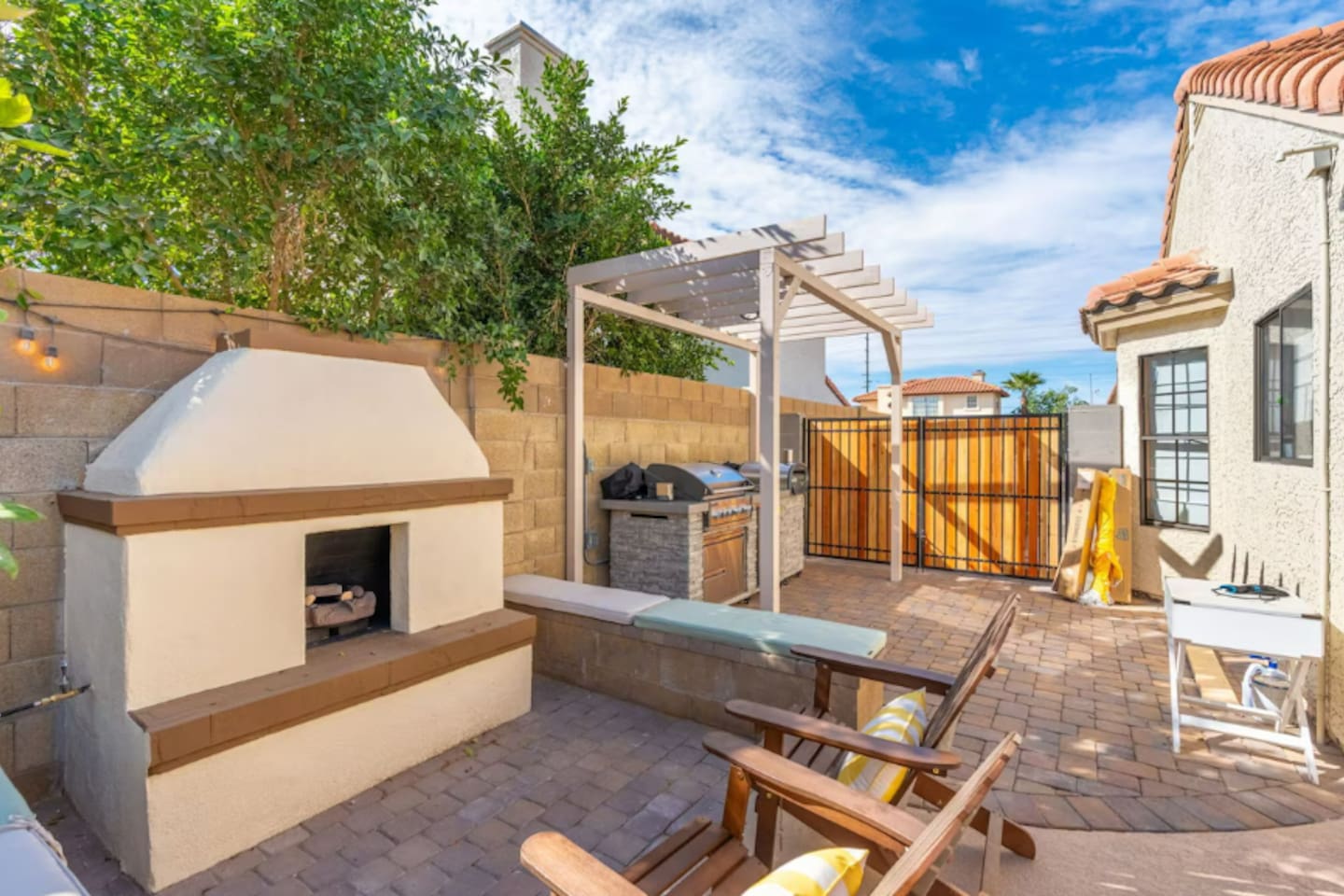 Multi-zone backyard with fireplace, pergola kitchen, loungers, and valley views—complete outdoor living and entertaining space.
