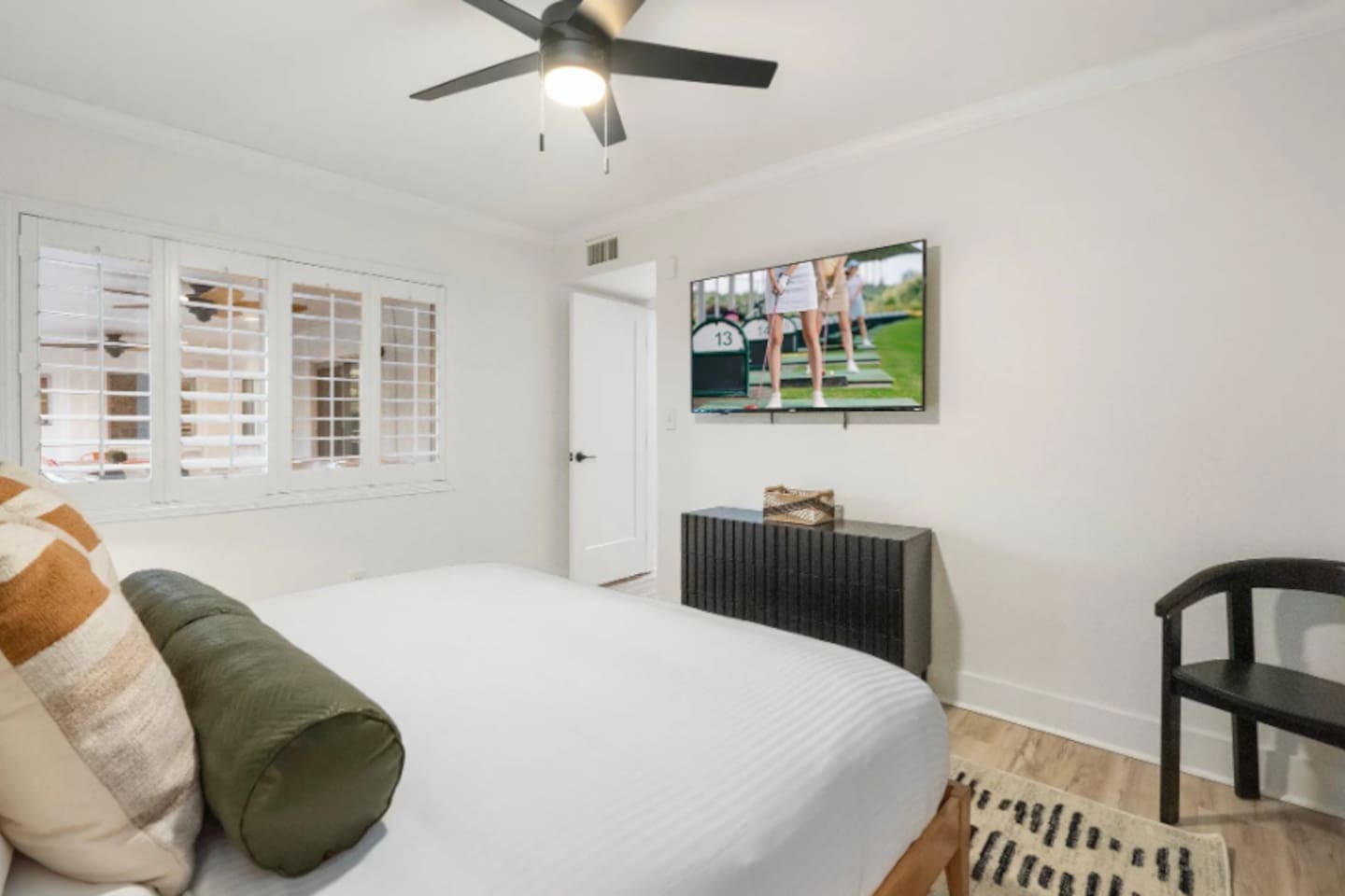 Soft morning light filters through the plantation shutters, making this room an easy place to wake up slowly. A wall-mounted TV and sleek dresser keep the space functional without crowding the calm.
