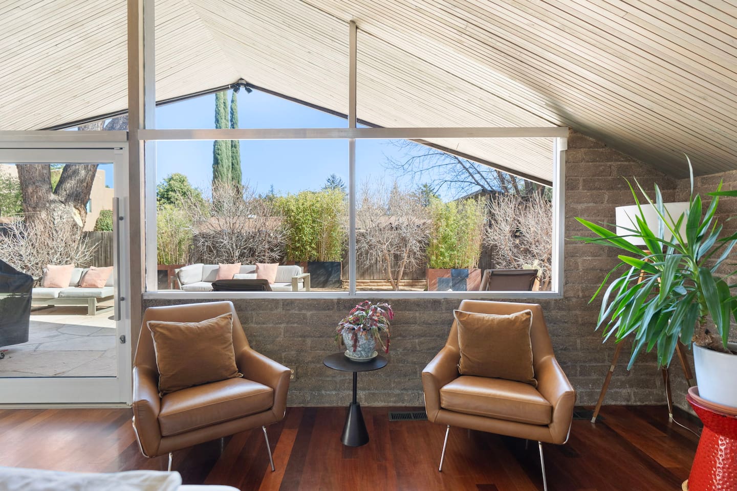 Cozy reading nook with floor-to-ceiling windows and peaceful backyard views.