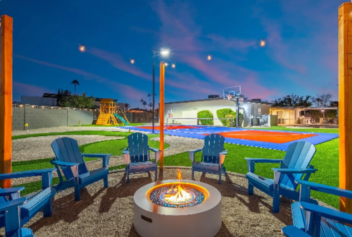 Evening falls and the fire pit lights up, with Adirondack chairs circled up for s'mores and storytelling. Just past the flames, a full sport court and play structure keep the fun going long after the sun sets.
