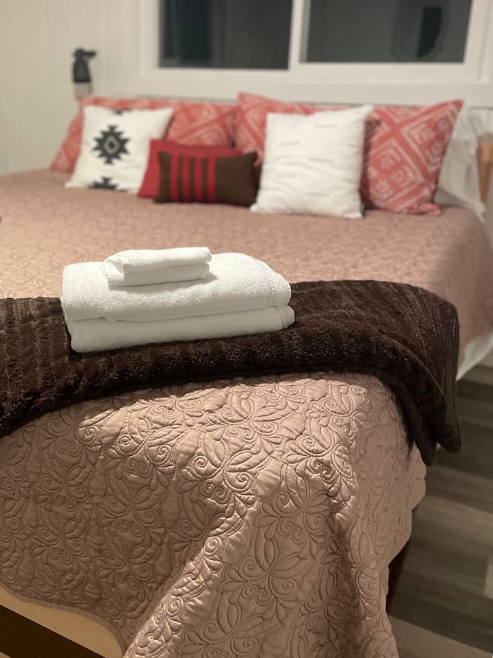 A fresh stack of clean towels ready for use, adding a touch of comfort and care to the bedroom.
