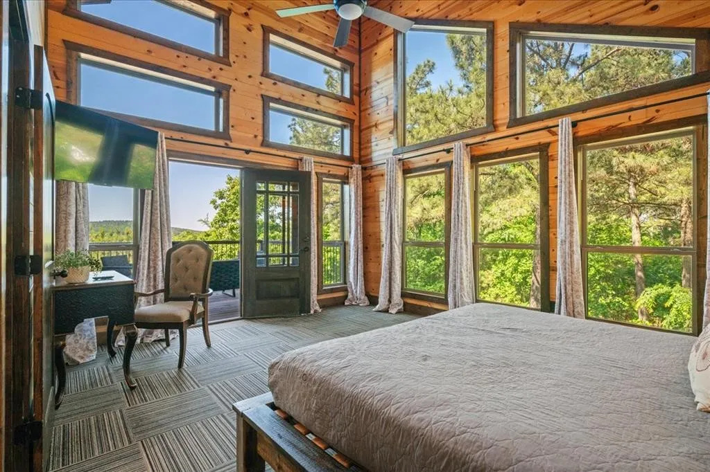 Upstairs bedroom with balcony access, shared bathroom to bunk room and TV.