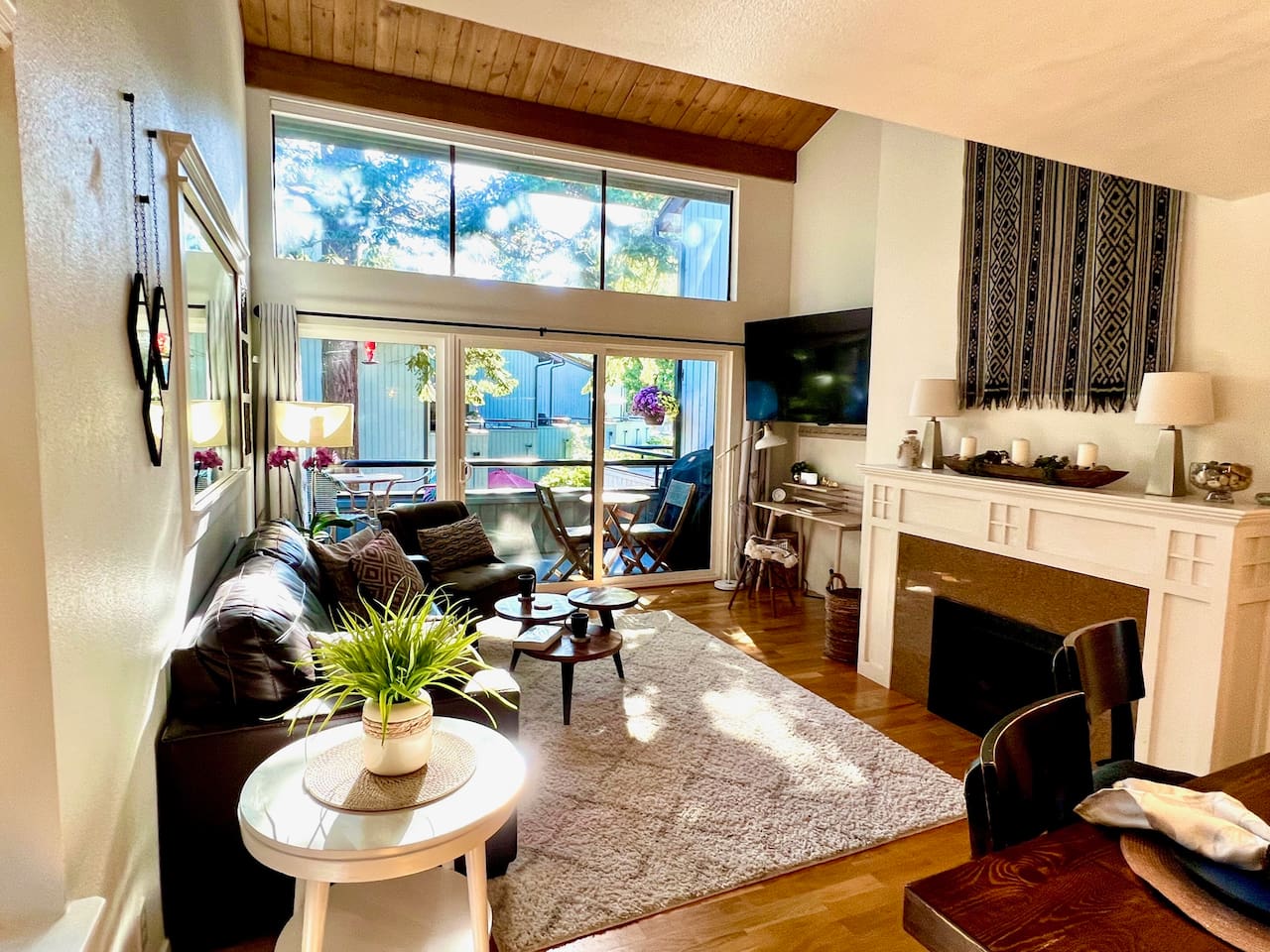 Living room with full wall of windows so you can enjoy the greenery on a sunny day or sit by a cozy fire on quiet fall and winter days