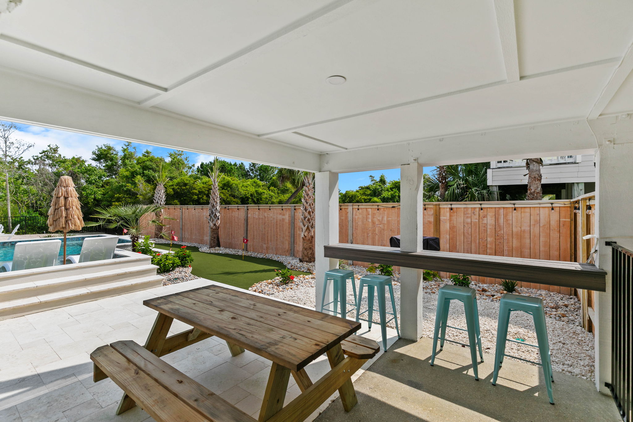 A covered outdoor hangout with seating and bar space gives the family another place to relax beside the pool.