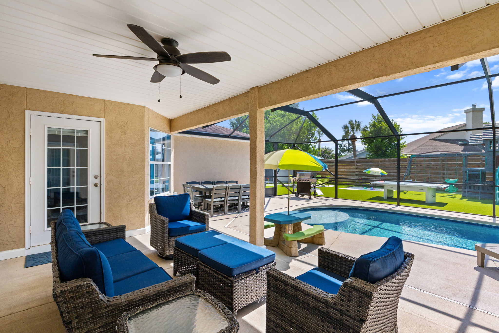 Relax under the shaded lanai! Features a 3-seat couch, 2 swivel chairs with ottomans, and a ceiling fan. The perfect spot to watch the pool and the kids hanging out at their own umbrella picnic table.