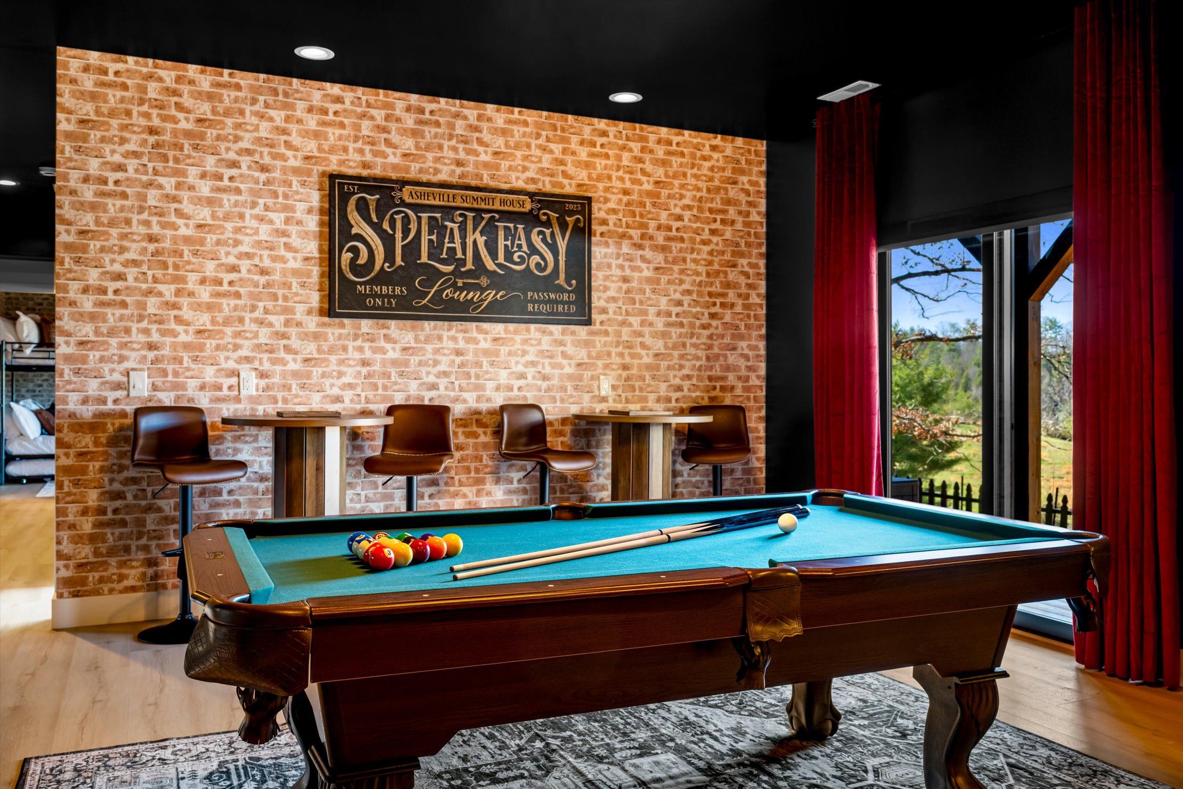 {Game Lounge} Unwind in our moody speakeasy-style lounge featuring a classic pool table, warm brick accents, and curated lighting. Perfect for late-night games, cocktails, and relaxed group hangouts, this space brings a unique, upscale twist to your stay.