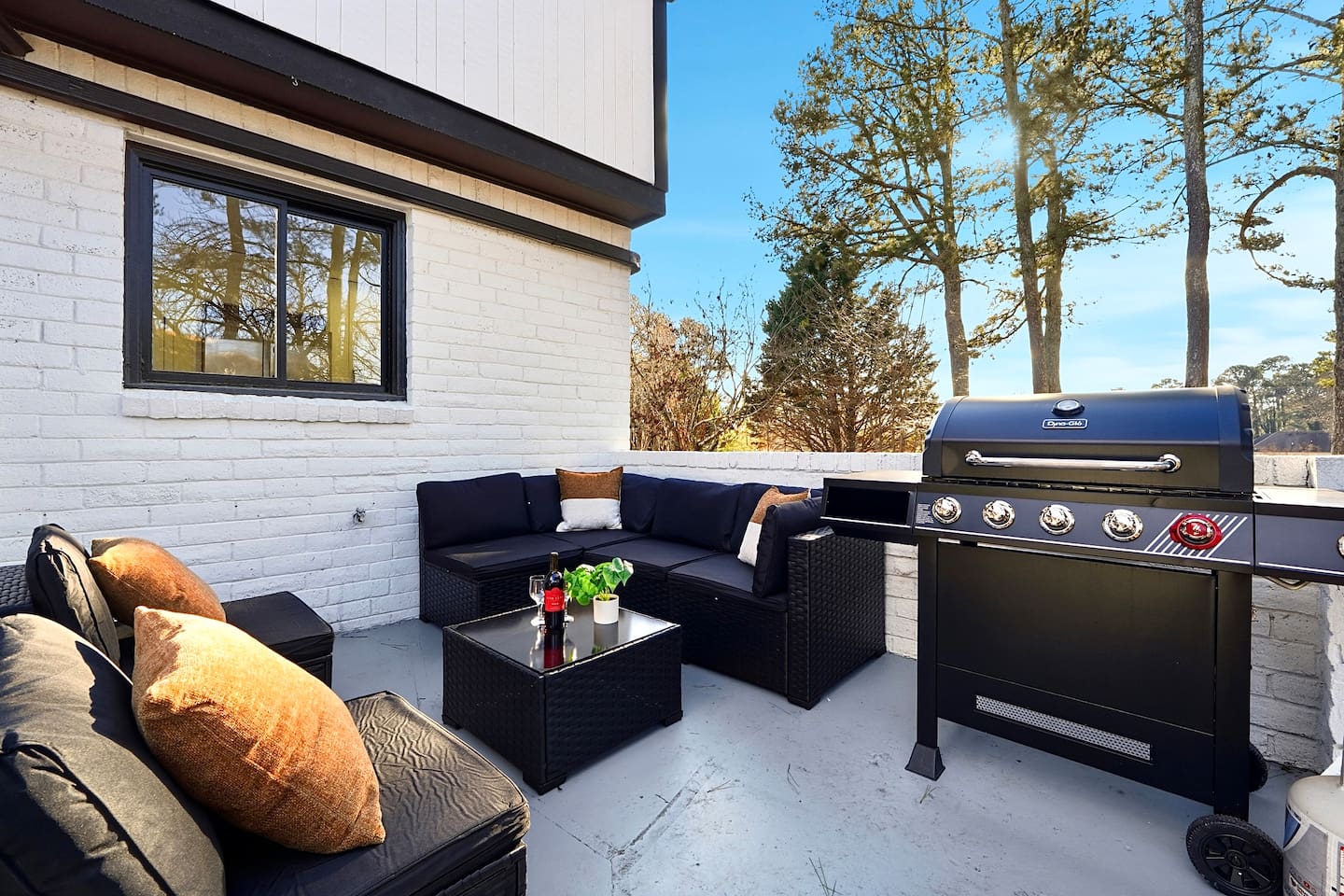 Inviting patio with black outdoor furniture, beige chairs, and a propane grill. A great space to relax, dine outside, or enjoy time with friends and family.