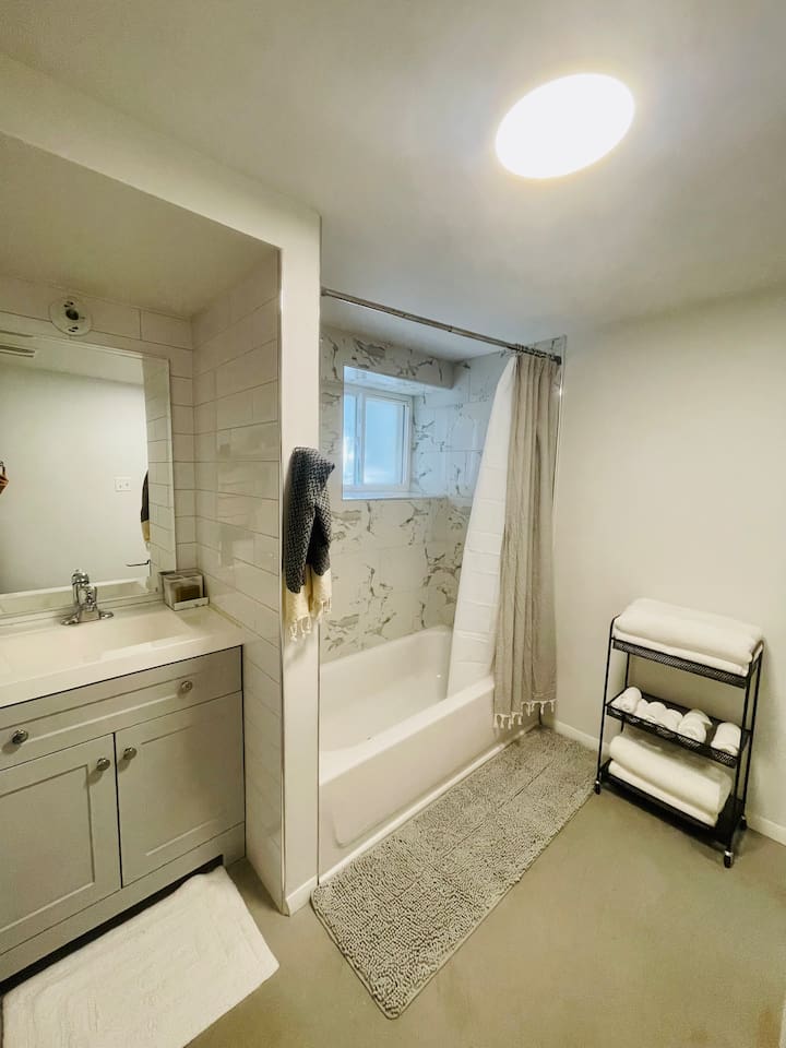 Clean and stocked bathroom with bath and shower and fresh towels provided.