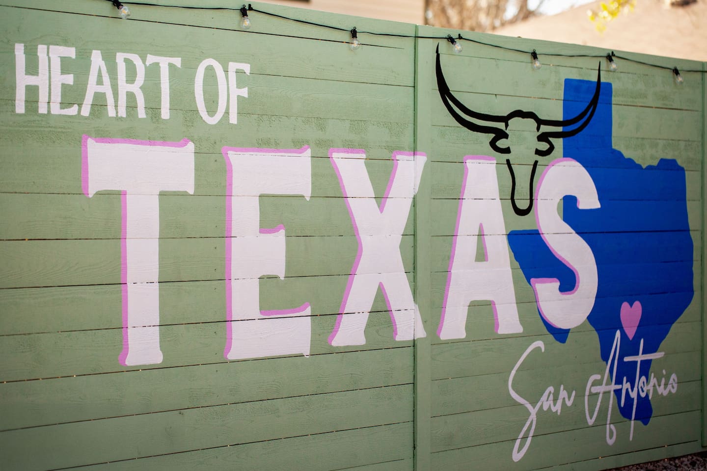 This mural says it all—**Heart of Texas, San Antonio**—painted in bold, playful lettering with a Texas longhorn and a heart marking the city. Perfect photo op for guests to show they’re deep in the heart of Texas! 