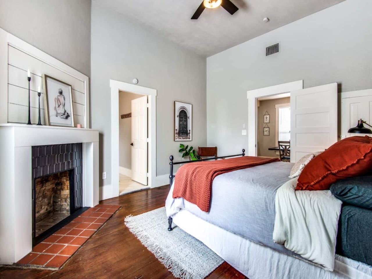 Full layout view of the king suite showing hardwood floors, decorative brick fireplace, ensuite entry, and ceiling fan. Spacious and bright in this renovated modern farmhouse in historic downtown Aubrey TX near Frisco and Denton.