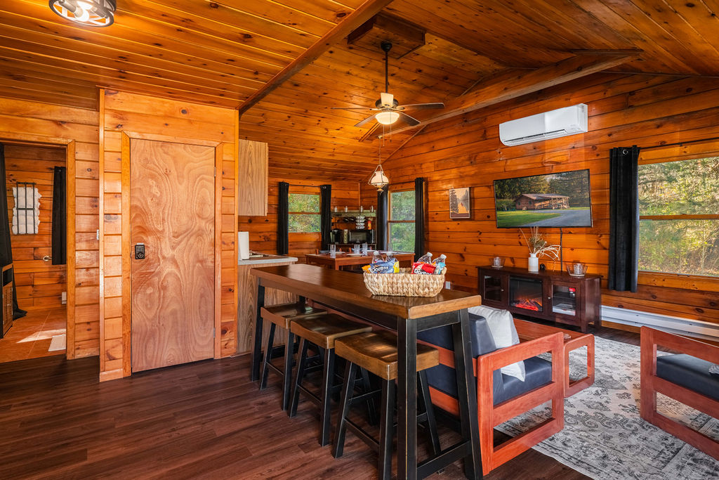 Bright and open living space with vaulted ceilings, large windows, and a cozy setup for movie nights or rainy day lounging.