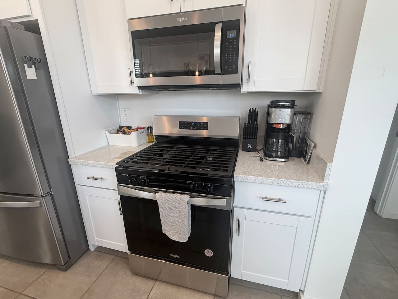 Kitchen stove area with microwave, coffee maker, and cabinets