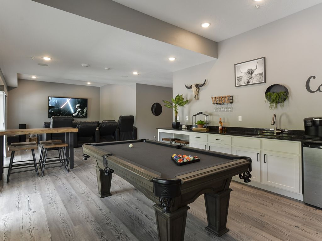 Downstairs living space with pool table and 85" TV with theater seating.