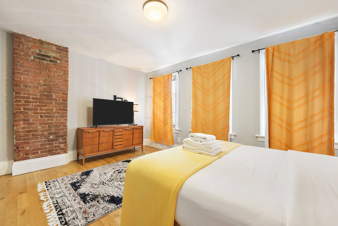 Comfortable queen-sized bedroom with a cozy workspace and TV — ideal for rest and productivity.