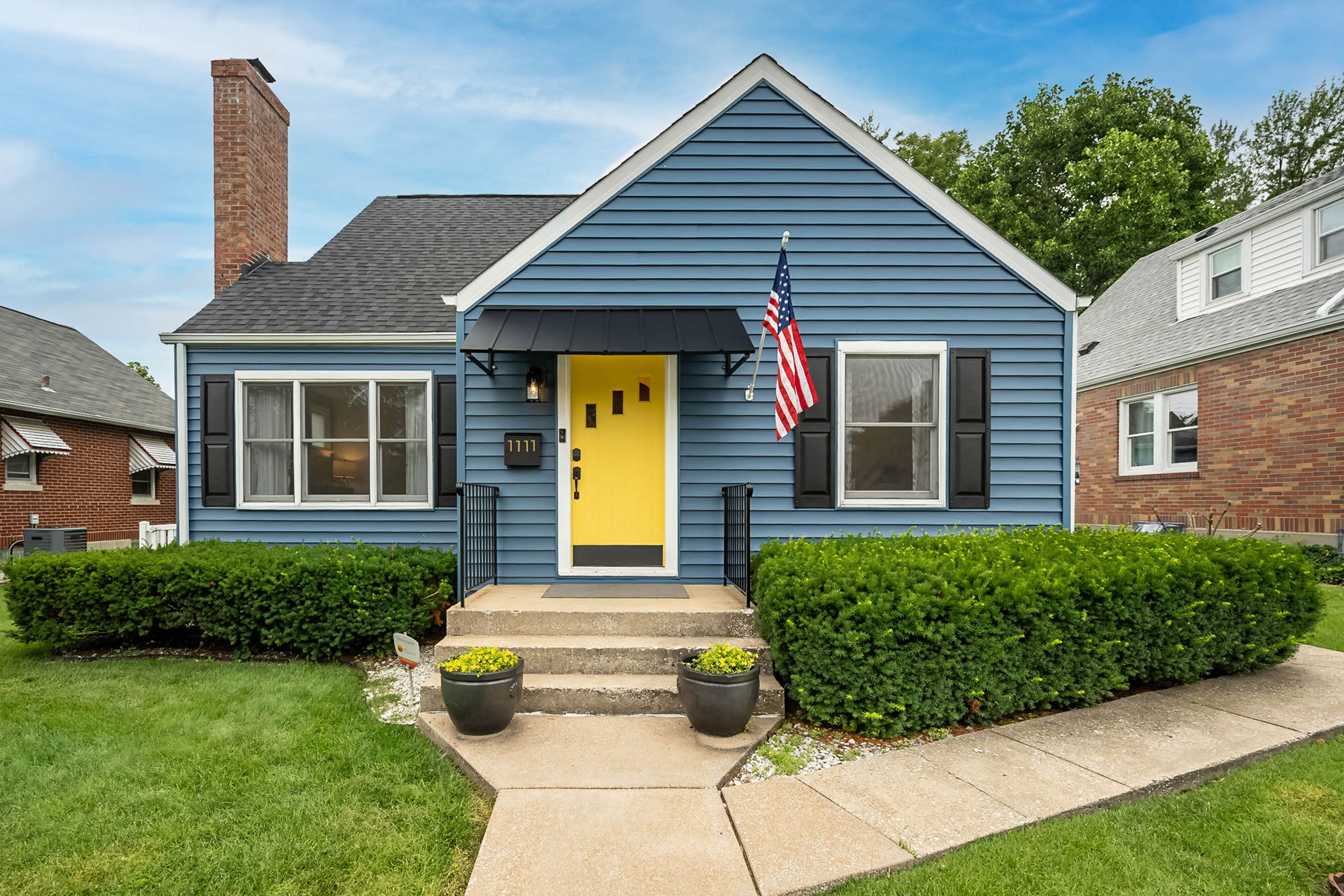 Cheerful blue bungalow with a bright yellow front door welcomes you home.