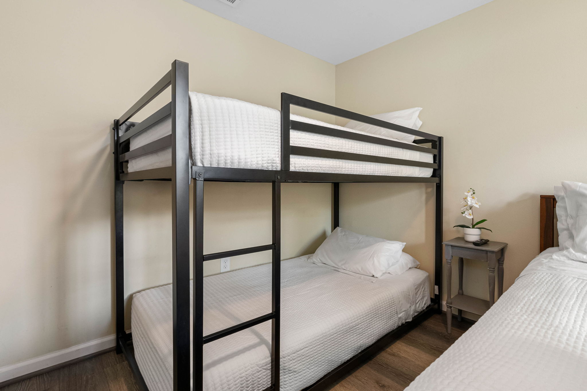 Alongside the king bed, a sleek black metal bunk bed offers cozy sleeping arrangements for kids or additional guests.