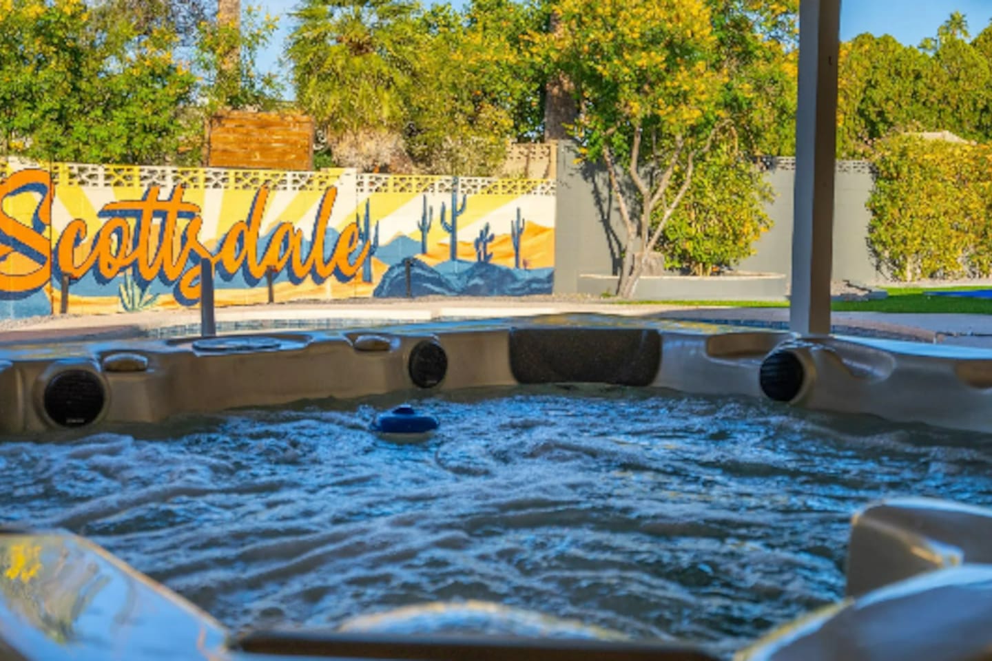 Bubbles rise in the hot tub while the hand-painted Scottsdale mural glows just beyond, a small detail that makes this backyard feel like nowhere else.