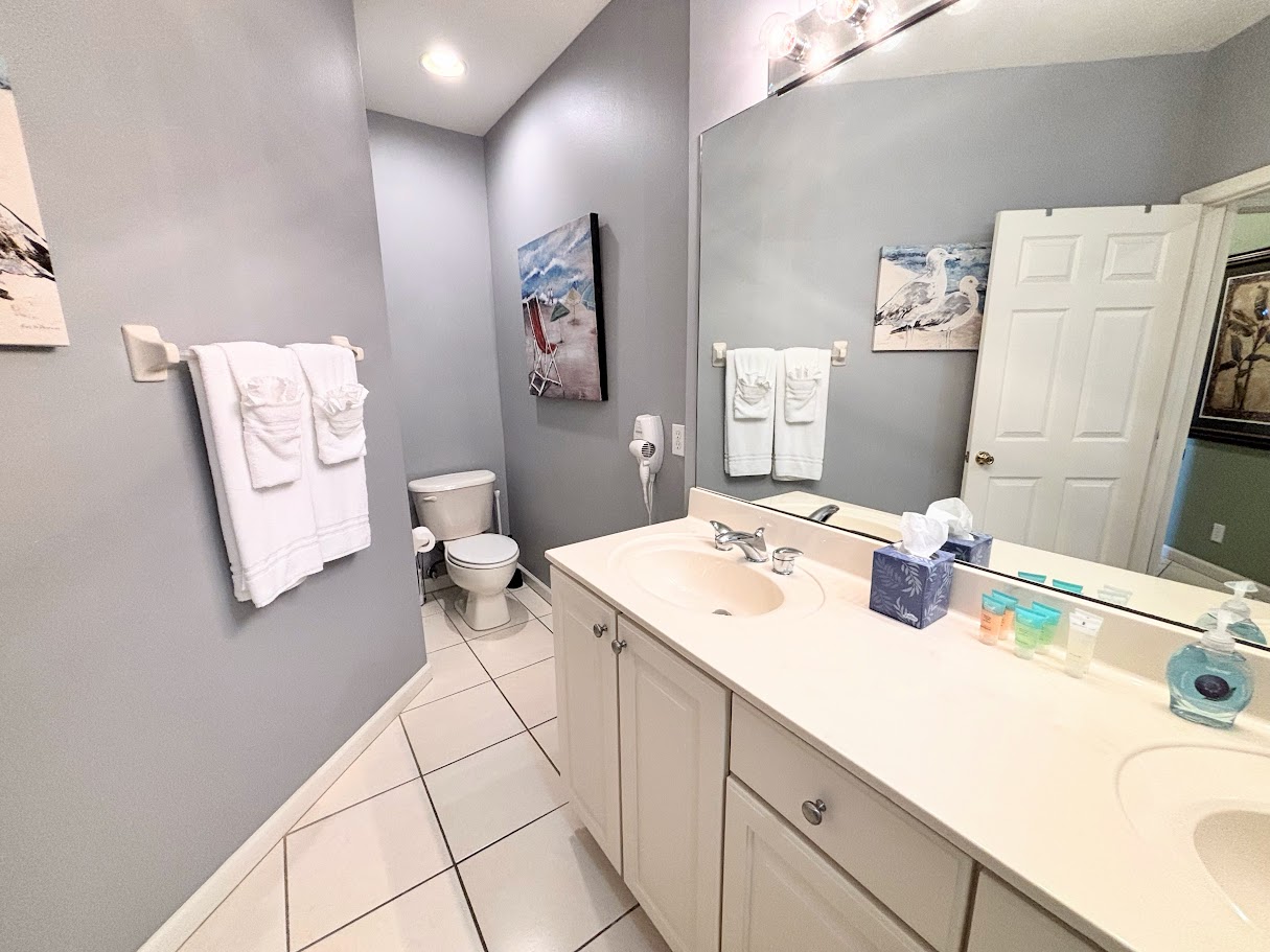 Clean and spacious bathroom with large vanity, tile flooring, and bright mirror lighting.